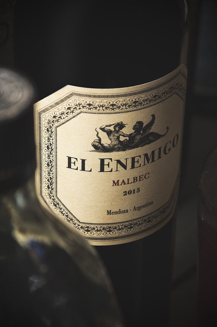 Botella de vino Malbec sobre mesa en penumbra