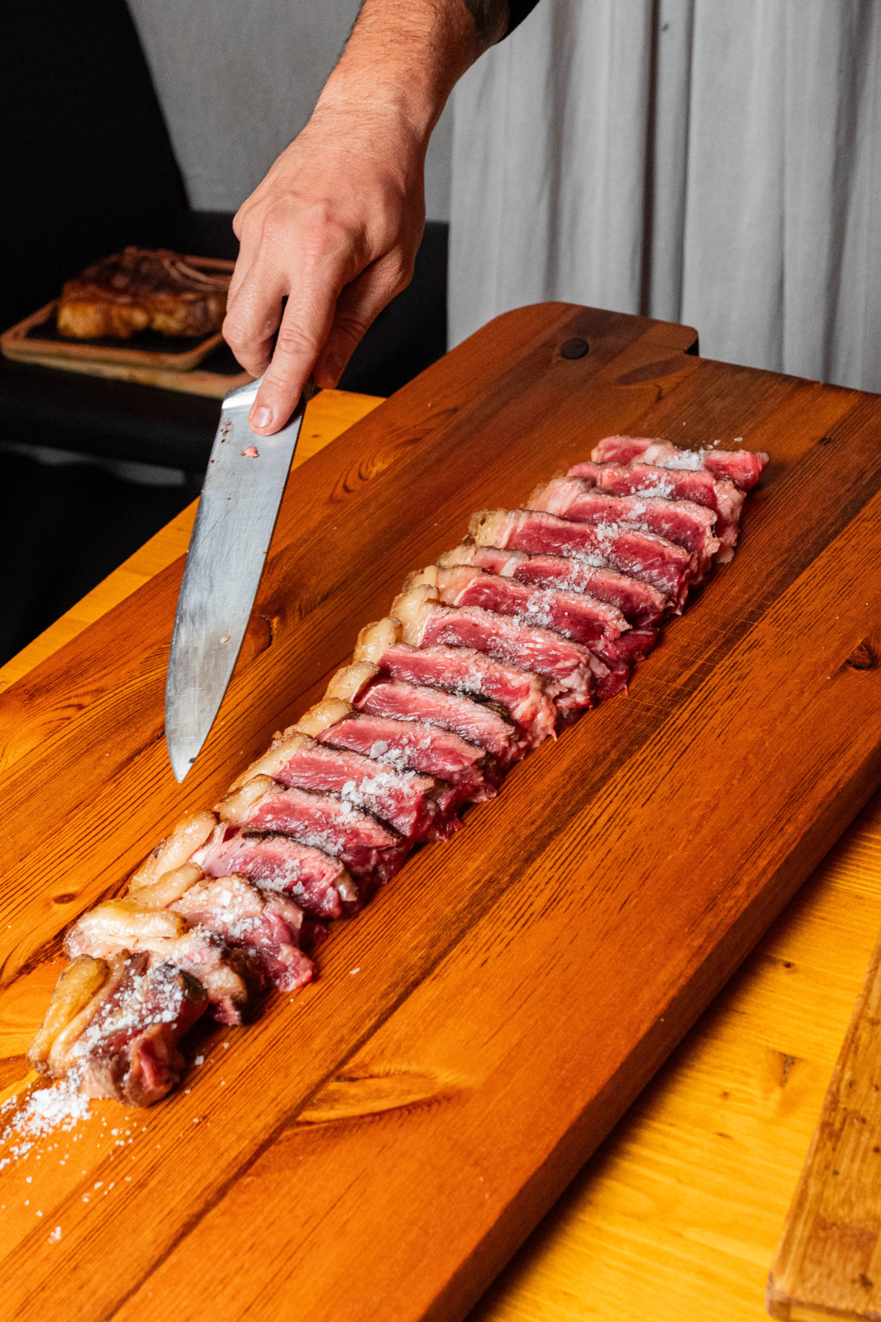 Chuletón cortado en láminas sobre tabla de madera